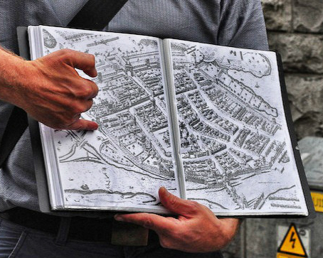Hands pointing out places on a historic city map.
